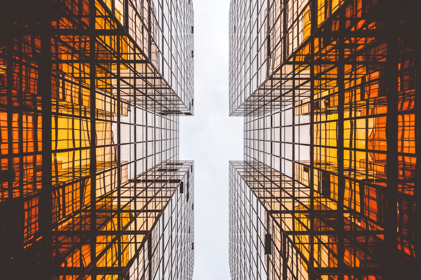Two mirrored glass towers glowing orange, seen from directly below