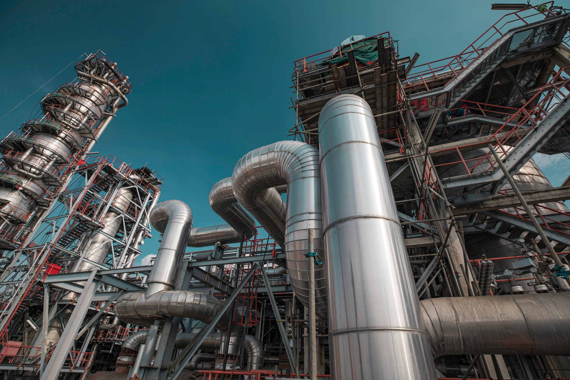 Close view of refinery columns and insulated piping against the sky