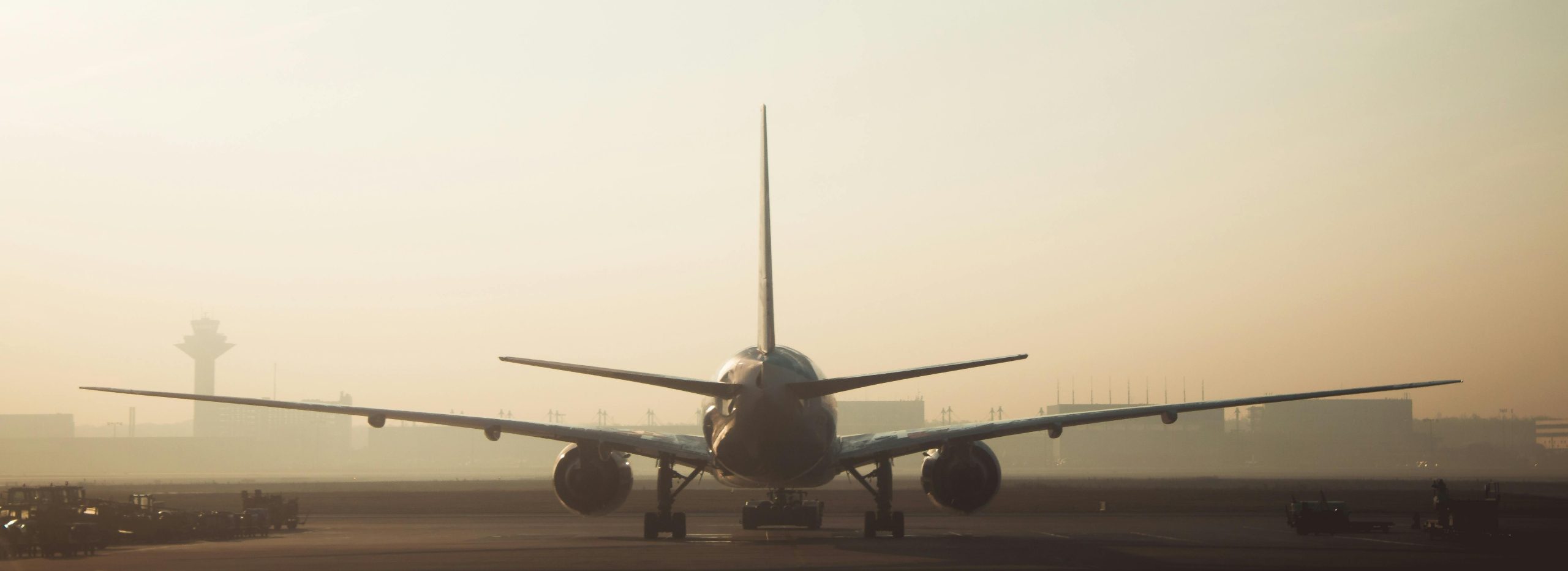 A jet airliner on a runway in hazy evening light, seen from behind
