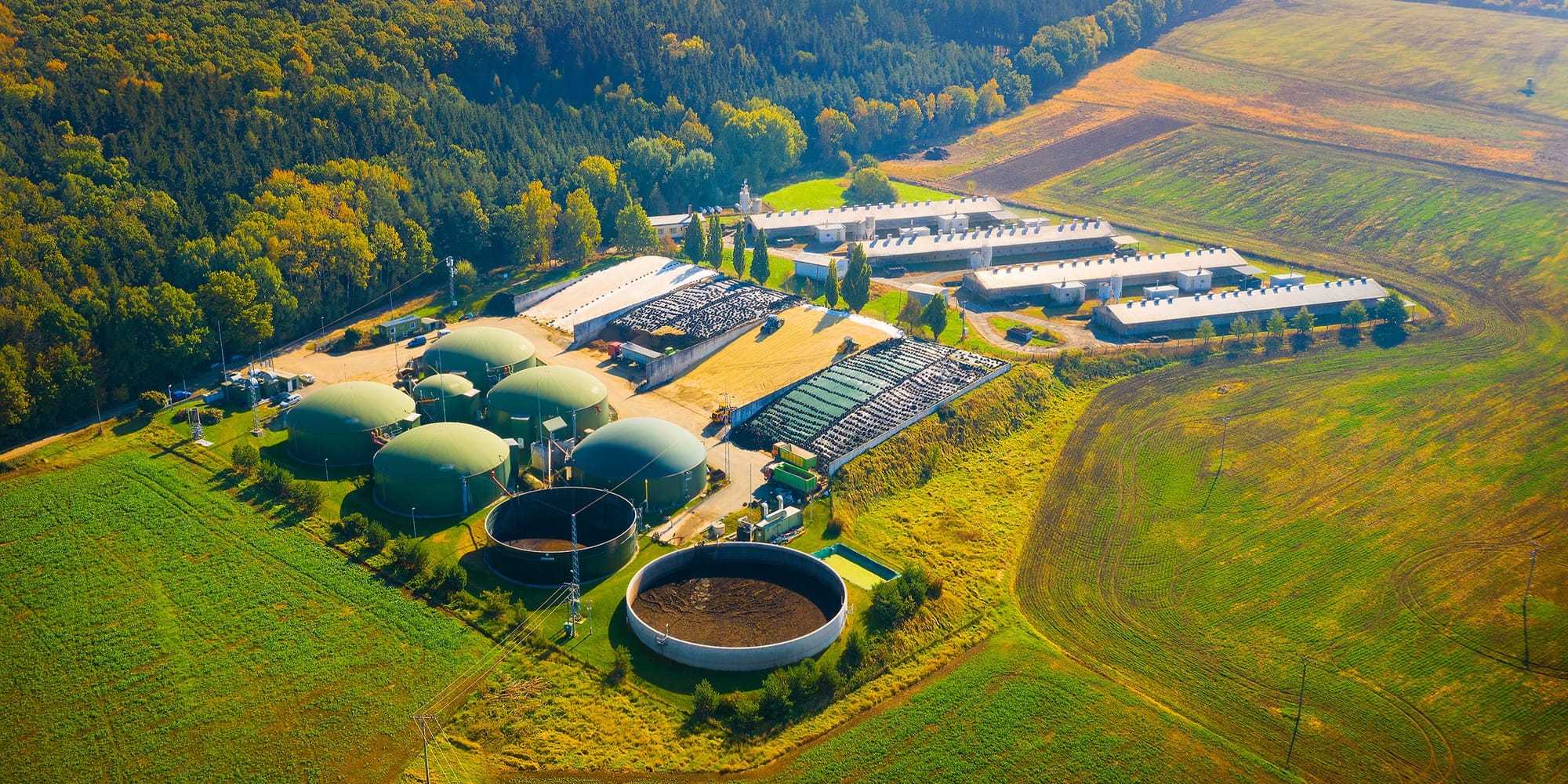 Aerial view of a farm anaerobic digester with domed tanks and a lagoon beside barns